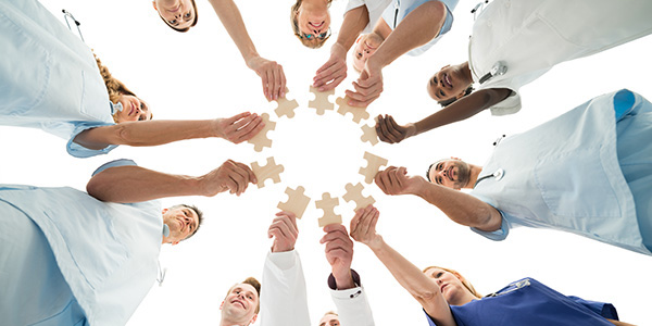 Les membres d’une équipe sont placés en cercle et tiennent chacun une pièce de casse-tête au centre, devant eux.