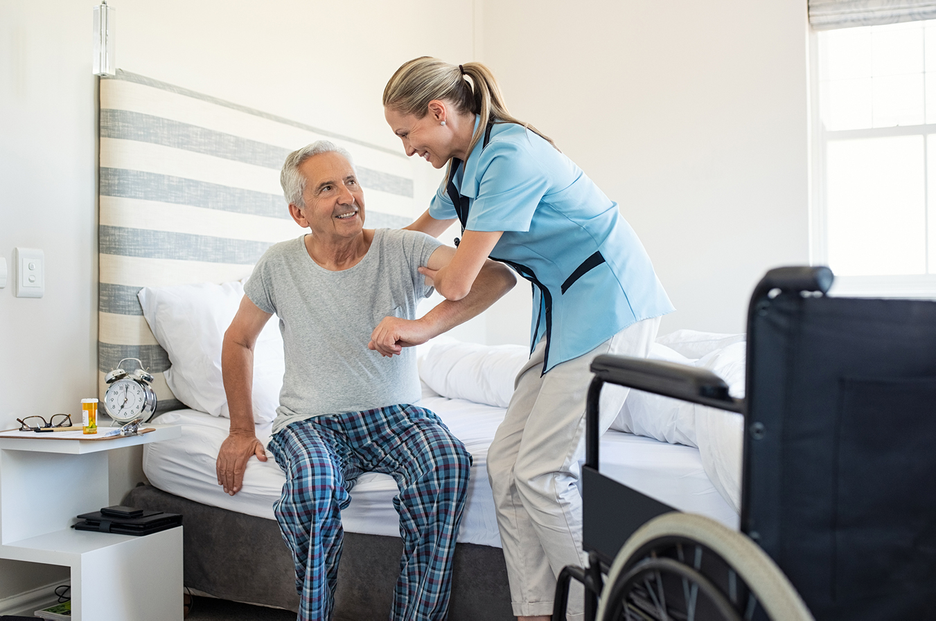 Une professionnelle aide un patient à se lever du lit