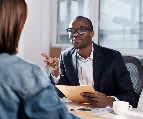 Un homme a la main ouverte devant une femme pour lui montrer qui l’invite à discuter