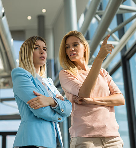 Deux femmes discutent et portent attention aux propos et aux indices non verbaux, comme les bras croisés, de l’autre