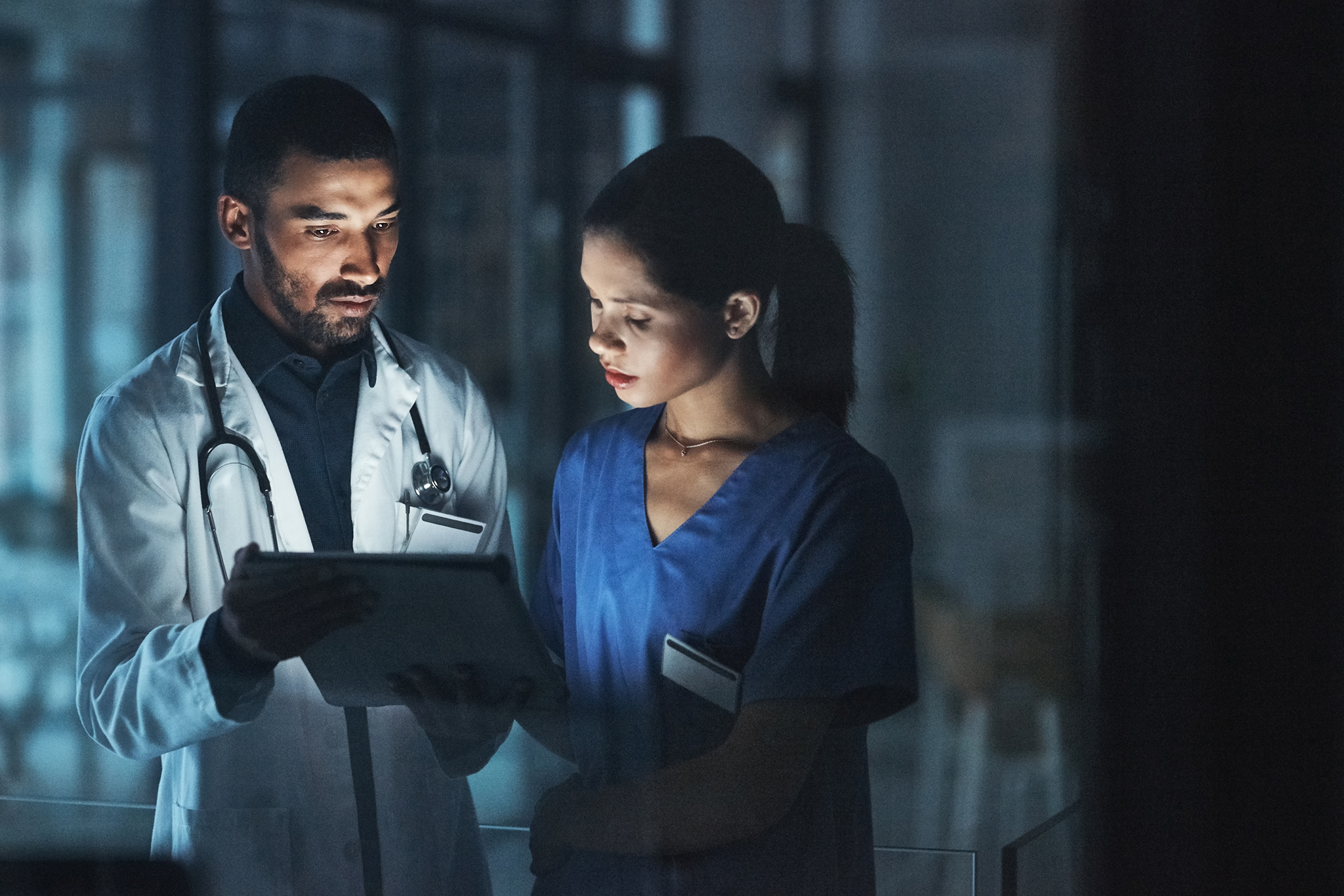 Deux professionnels qui travaillent de nuit consultent une tablette