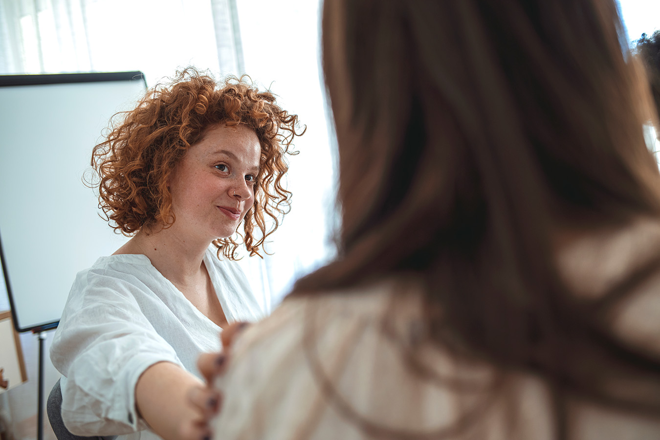 Une femme au regard bienveillant dépose la main sur l’épaule d’une collègue