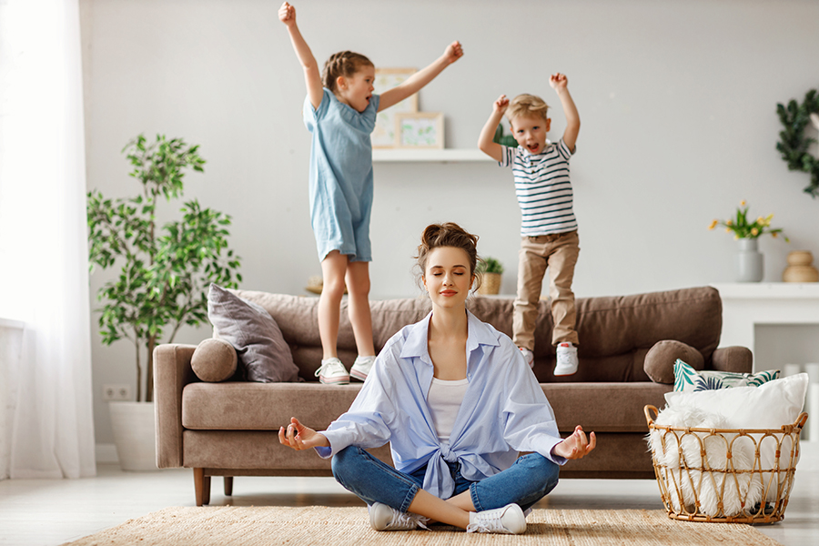 Une mère médite pendant que ses enfants sautent sur le divan