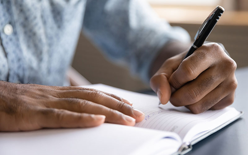 Un professionnel écrit dans un carnet de notes.