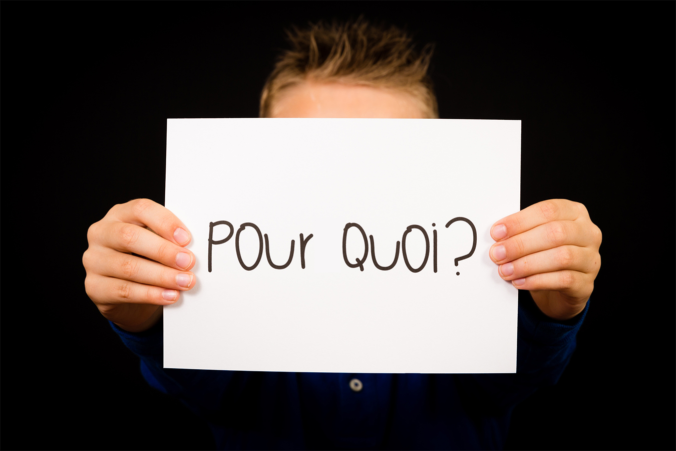 Les mains tenant une feuille avec les mots « POUR » et « QUOI » suivis par un point d’interrogation.
