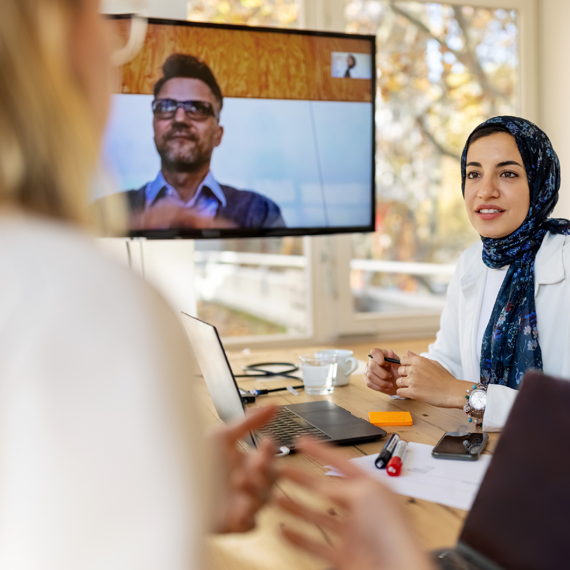 Une stagiaire discute des documents de stage avec la personne-ressource et son superviseur qui est à distance