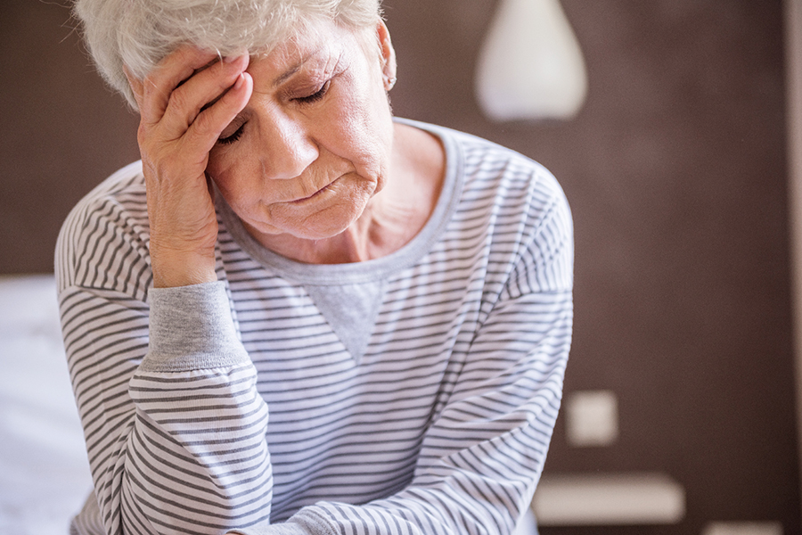 Une femme de 65 ans repose sa tête sur sa main, les yeux fermés