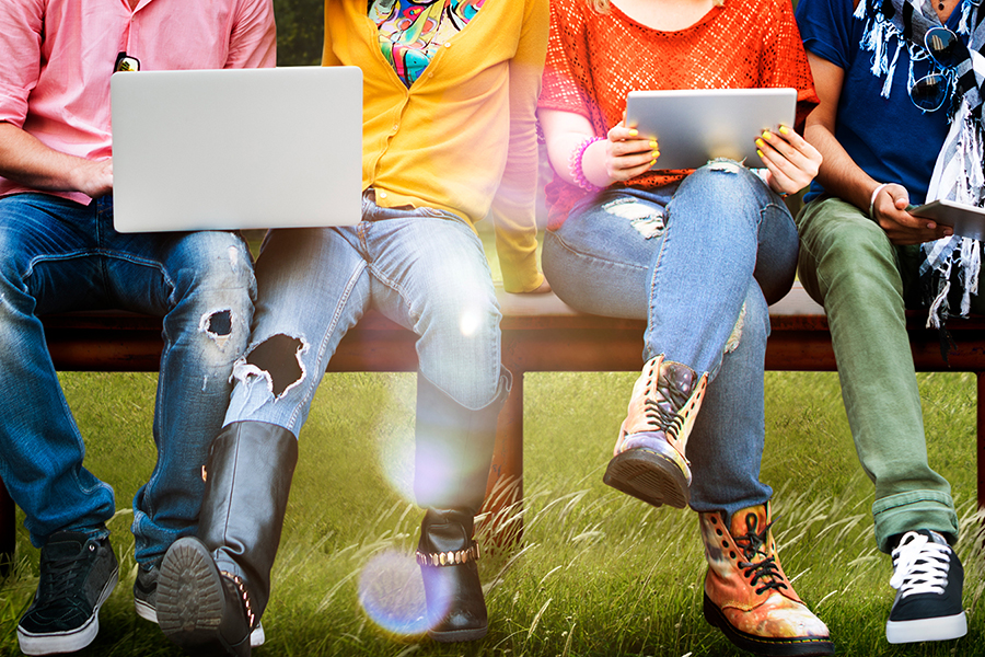 Adolescents assis sur un banc et travaillant avec des ordinateurs