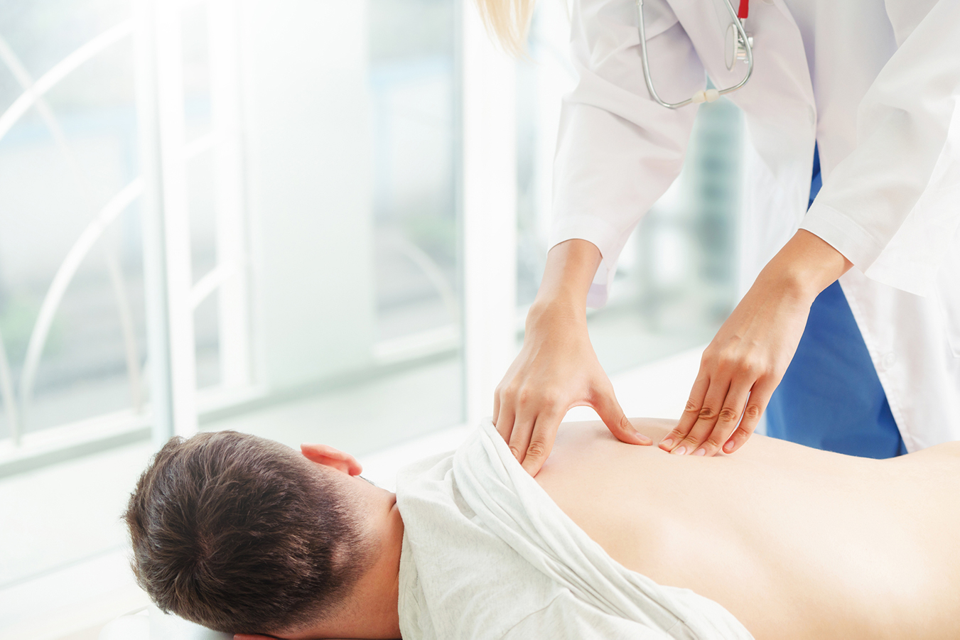 A professional completes an intervention by laying her hands on a patient’s back. 