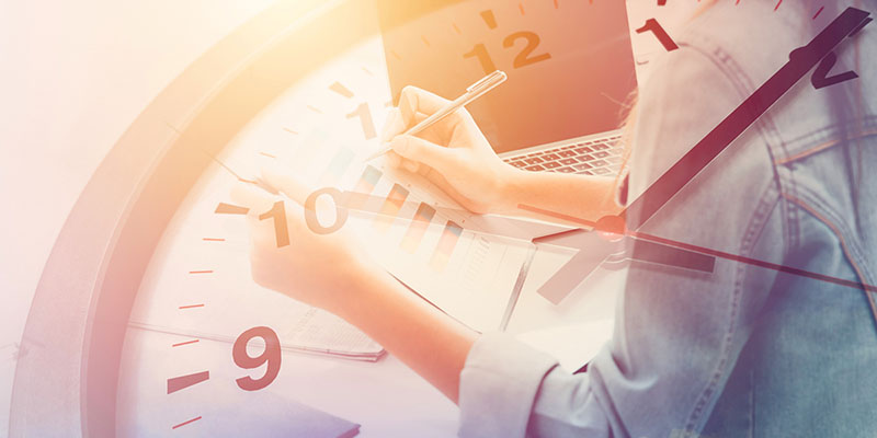 A professional is taking notes on observations made during the day. A clock is displayed in the background