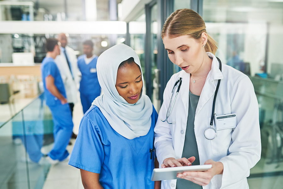 A supervisor is having a discussion with her trainee, showing her data on a tablet.