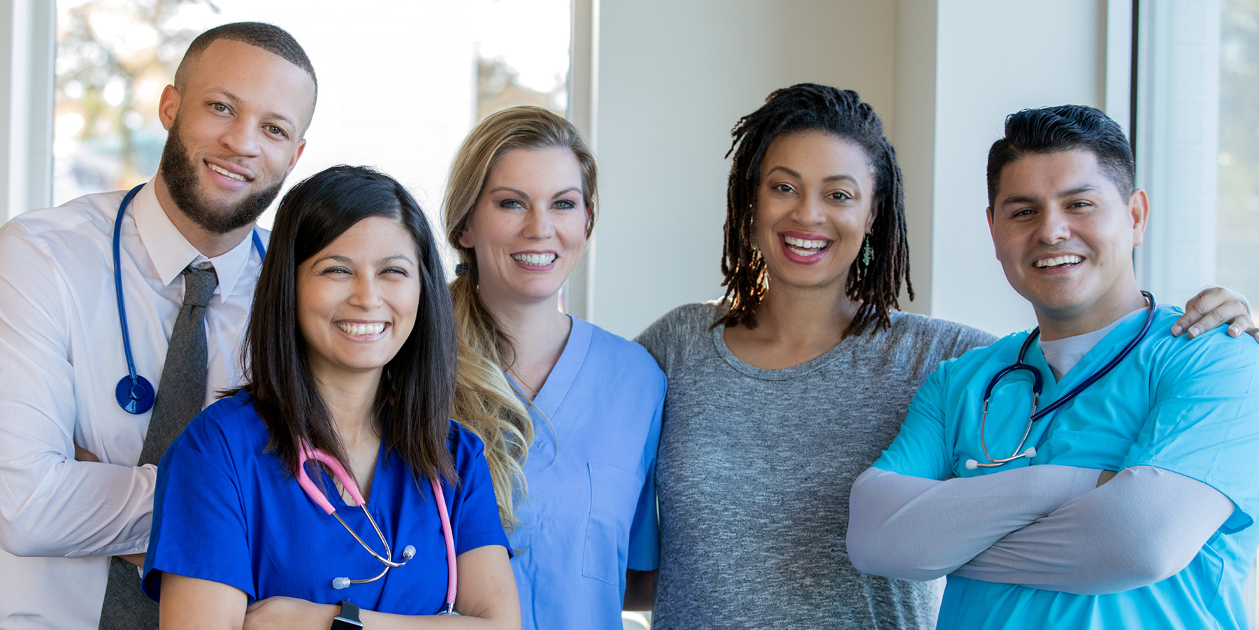 A trainee with her supervisor and colleagues stand shoulder to shoulder, smiling.