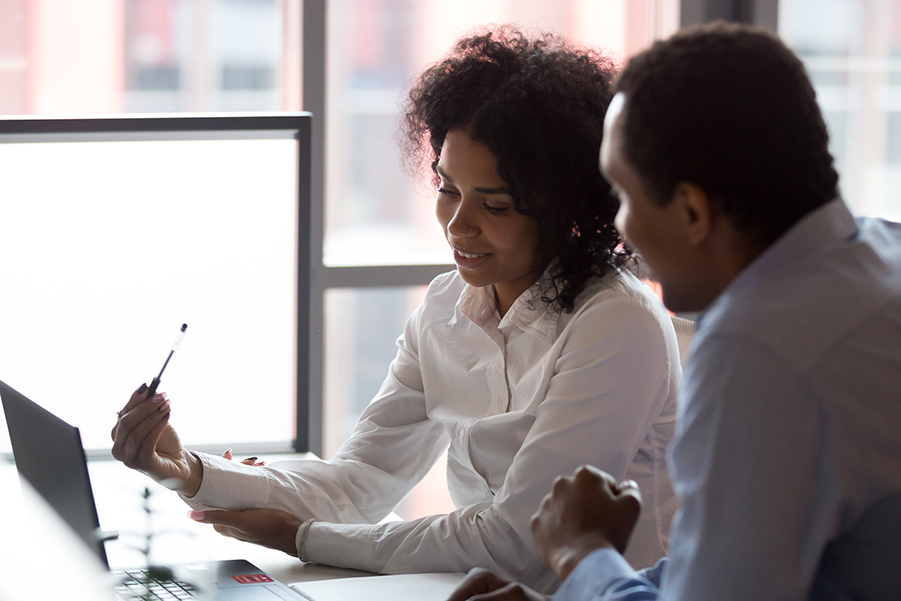 = A supervisor is having a discussion with her trainee in front of her computer.