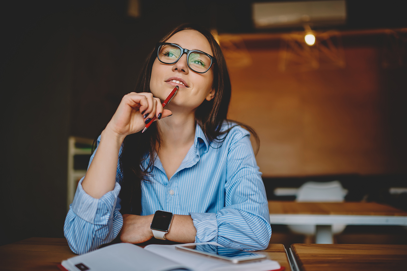 A student sitting in front of her study books reflects, a pencil on her chin.