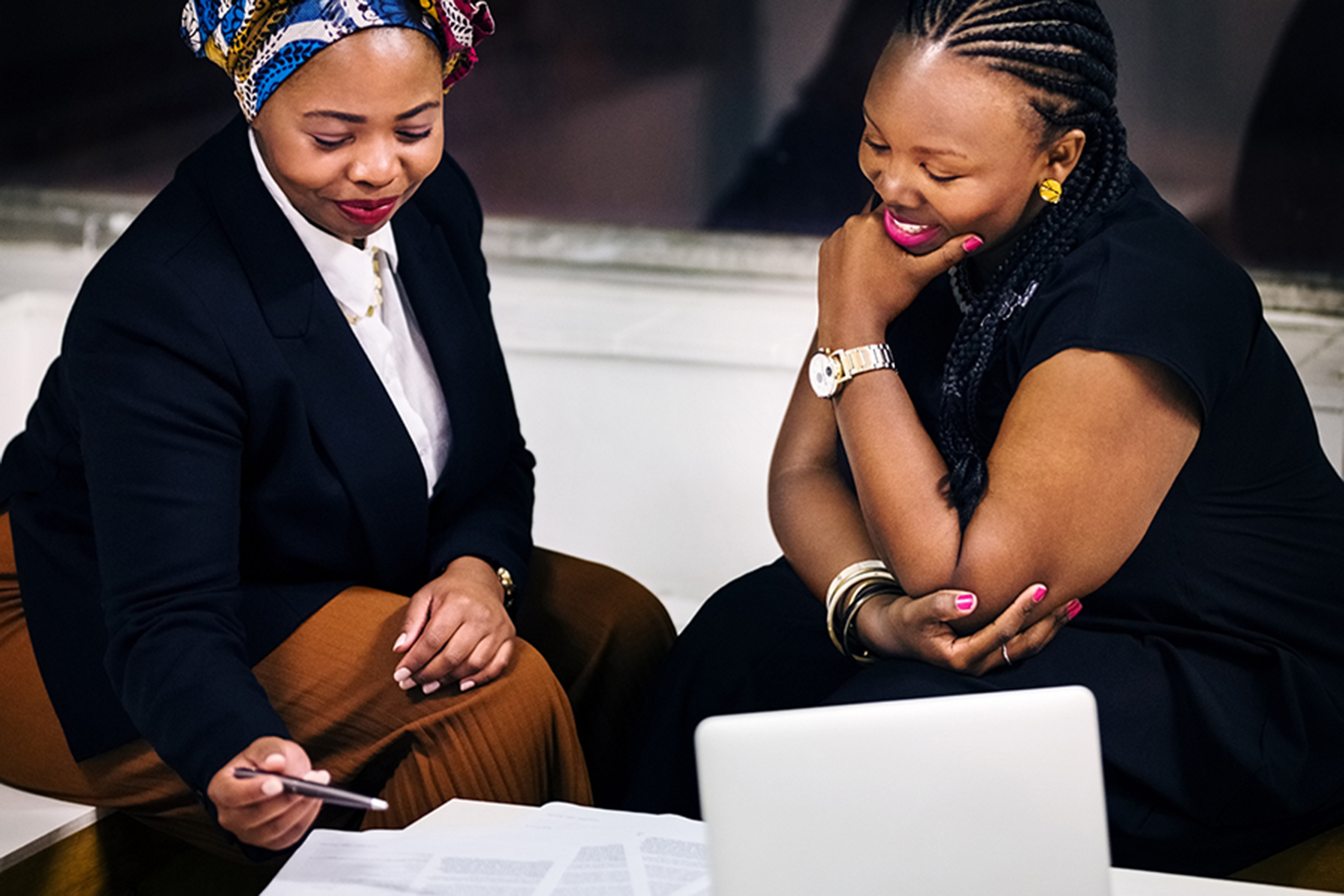 Two women are having a discussion in front of a computer.