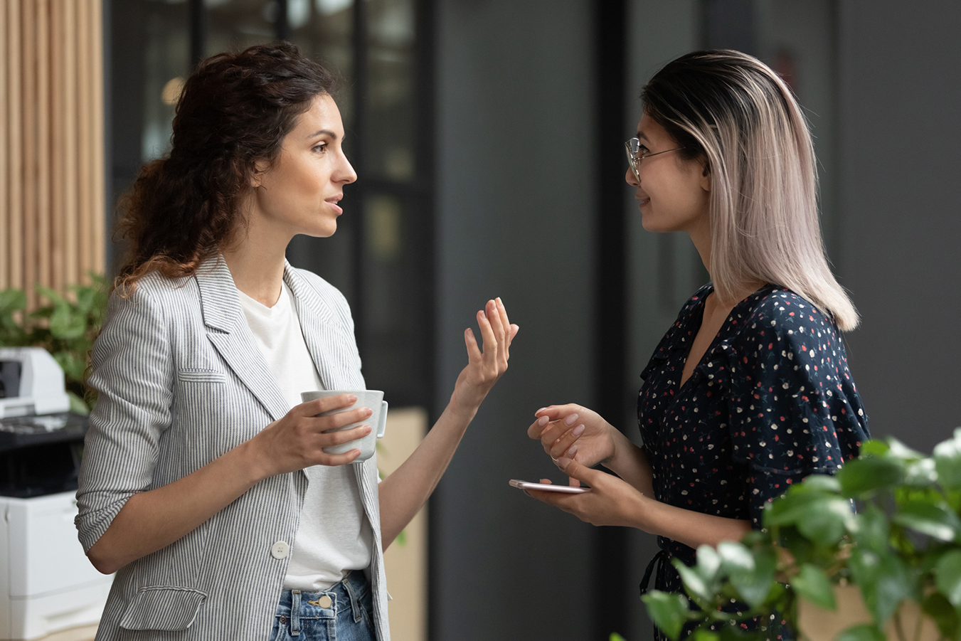 A supervisor and a trainee, standing facing each other, are having a conversation.