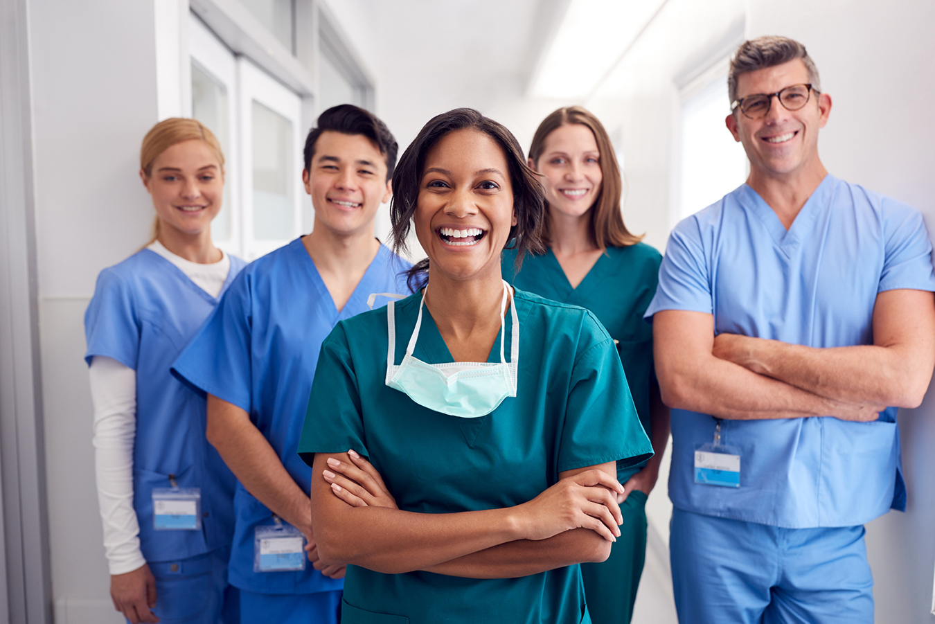 A group of trainees from different cultures wearing hospital uniforms.