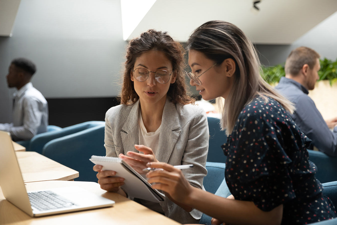 A supervisor shows observations written on a notepad to her trainee.   