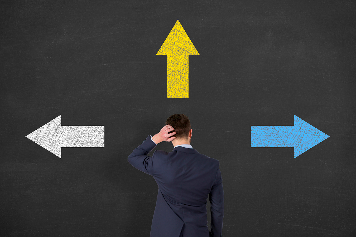 A man is looking at a board displaying arrows going in three direction.