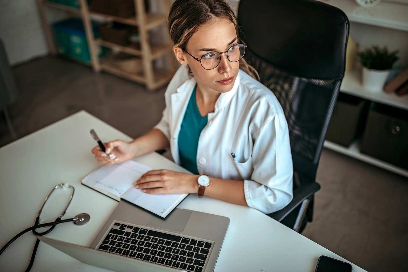 A supervisor, sitting at her desk with her notebook, is thinking about what she wants to use as data.