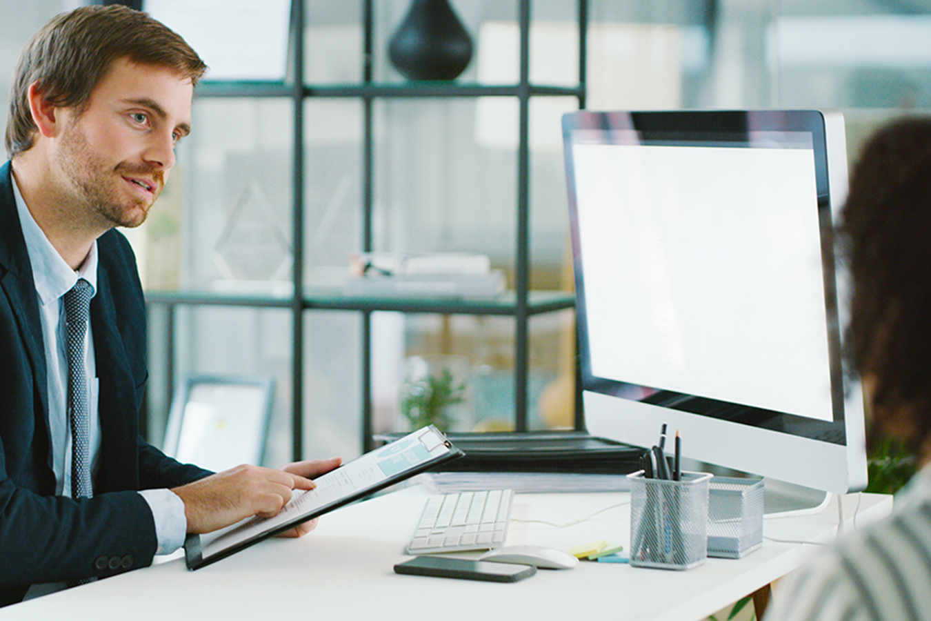 A supervisor sitting with his trainee explains the objectives that are listed on the document he has in hand.