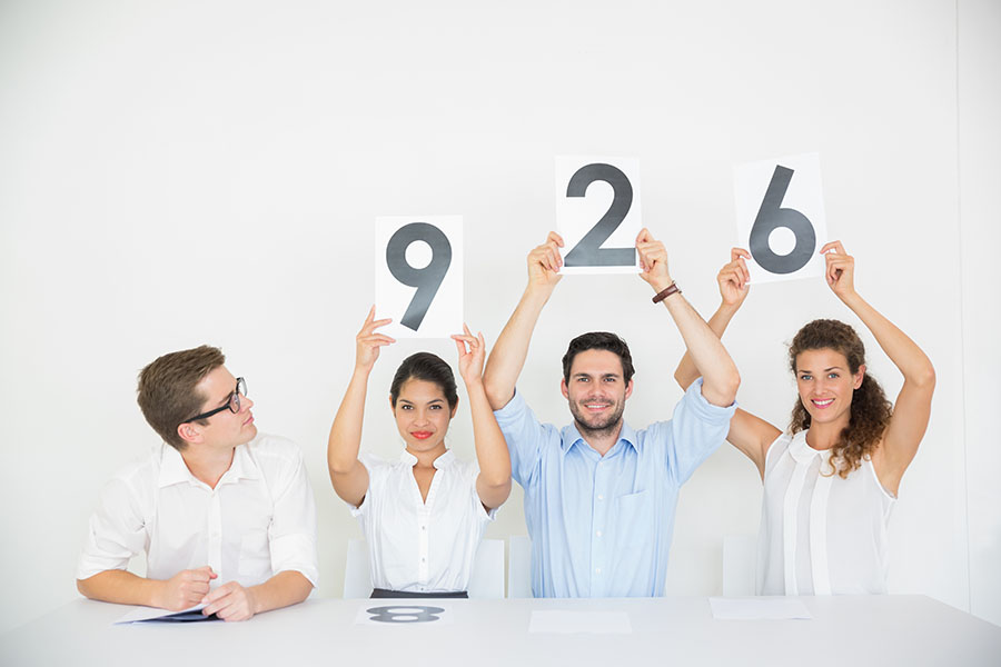 In plain view, assessors display different marks written on a paper they hold above their heads