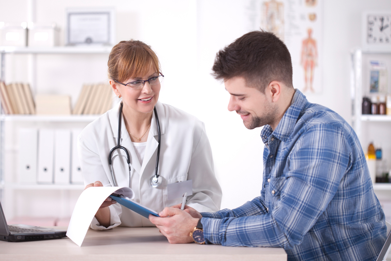 A smiling trainee and his supervisor look at a list of expectations.