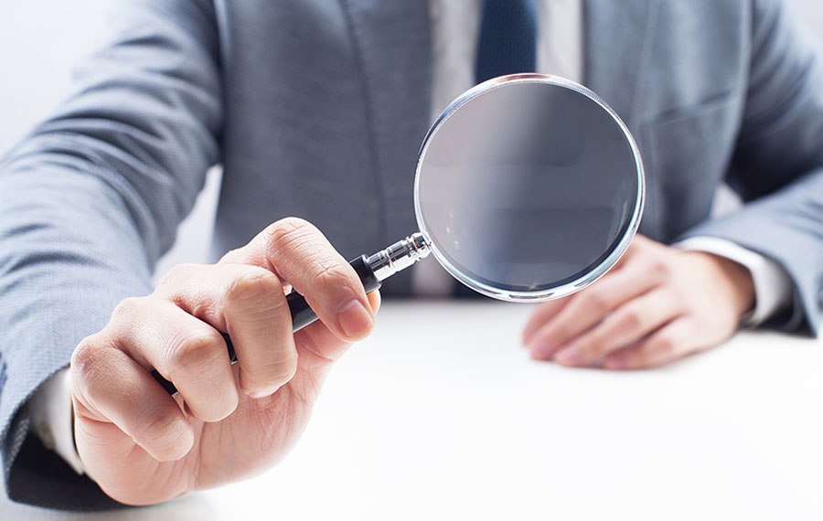 A professional is holding a magnifying glass and looks through it.